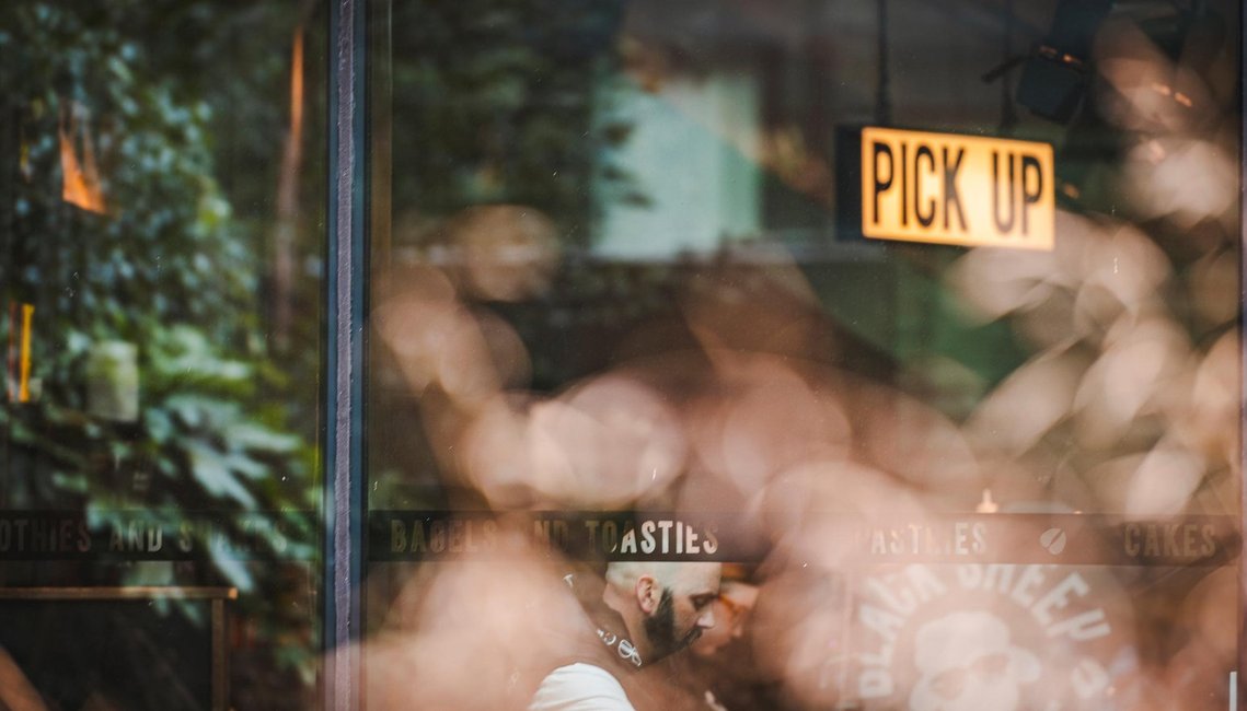 URBAN LIFESTYLE AND LOCAL AREA PHOTOGRAPHY OF SPINNINGFIELDS, MANCHESTER, architecture shot showing view into a coffee shop window with man sat looking down