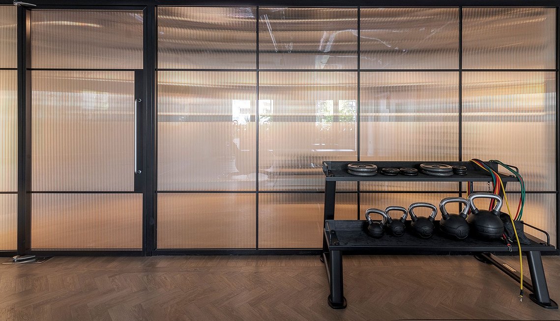 Modern gym with frosted glass walls and kettlebells on rack.