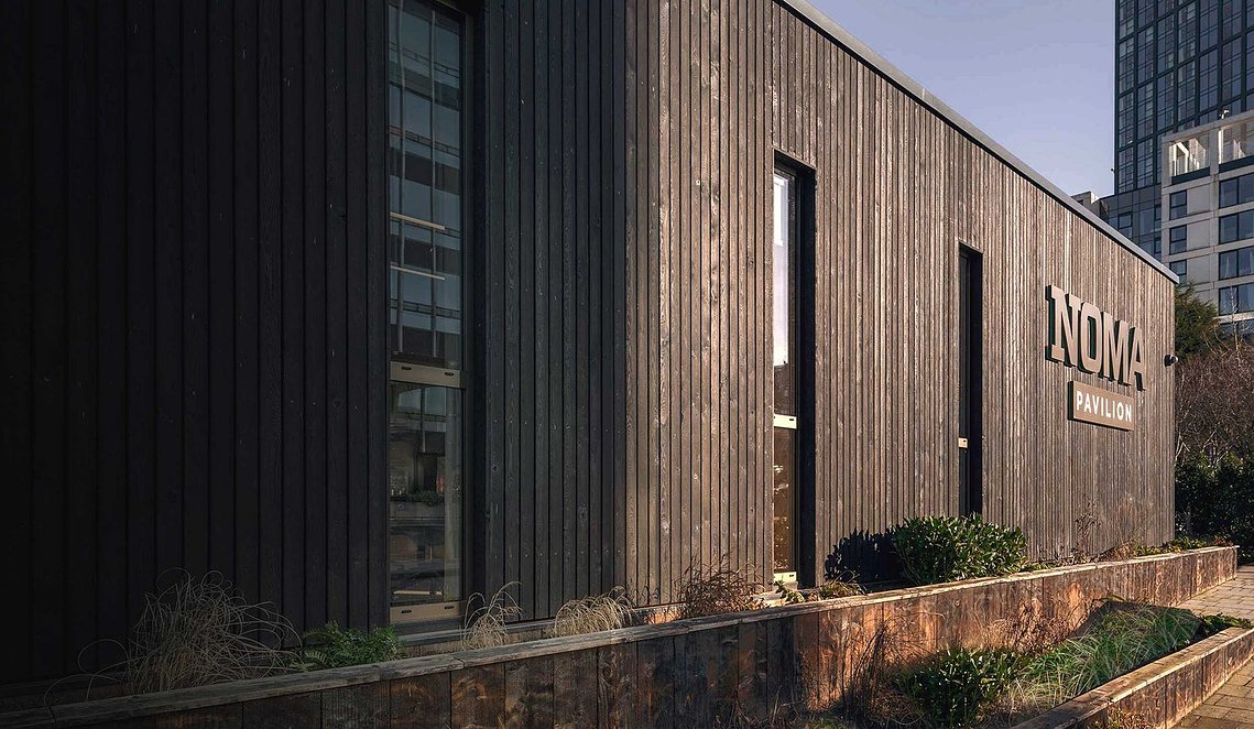 exterior of wooden clad building with low sunlight

