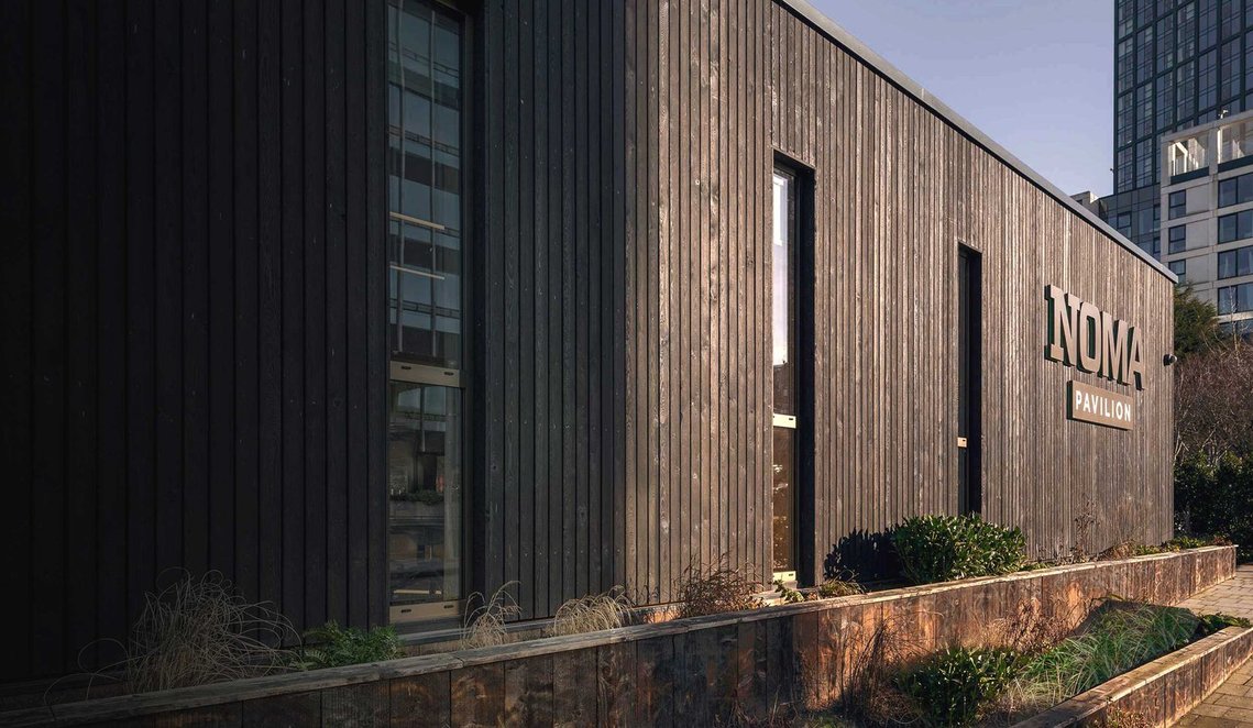 exterior of wooden clad building with low sunlight
