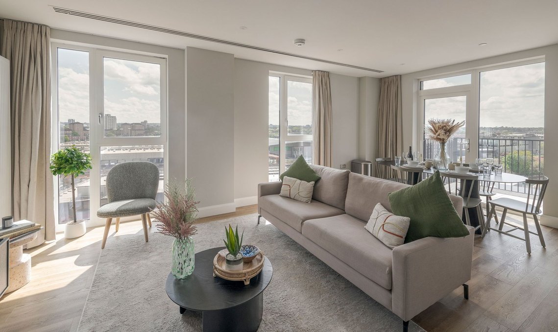 commercial interiors photography, Modern living room with sofa, chair, and dining area overlooking cityscape through large windows.