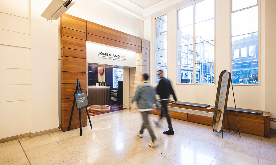 optician and client walk across the lobby in reception of building