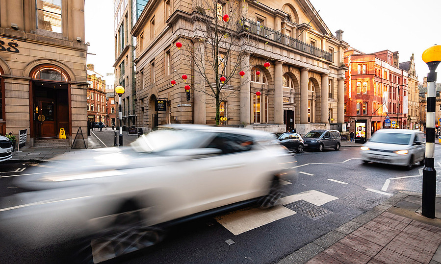 period building on manchester busy street with cars and people whizzing by