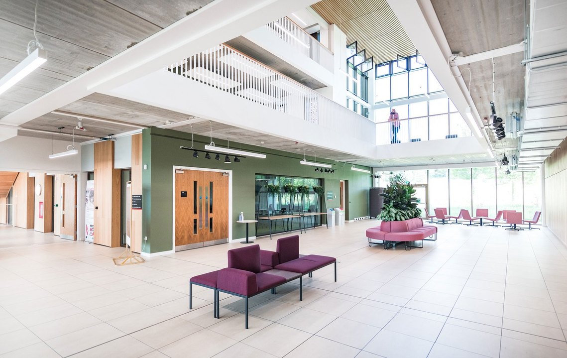 Modern spacious lobby with seating, large windows, and multi-level walkways.