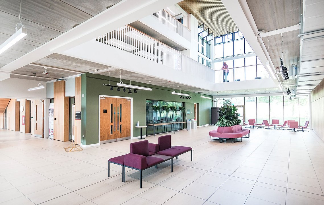 Modern spacious lobby with seating, large windows, and multi-level walkways.