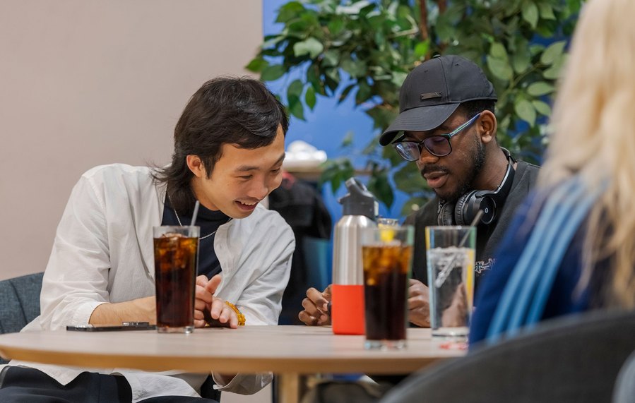 student lifestyle photography, two students sit with drinks chatting