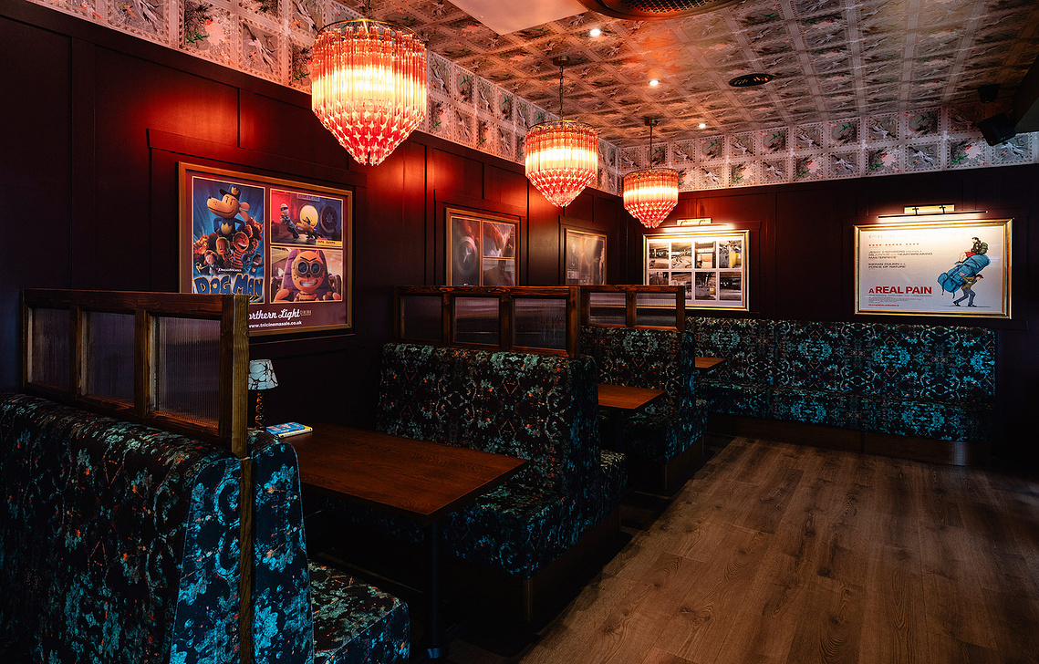 dining booths in a cinema lobby, colourful patterned fabric on seating and movie posters on wall