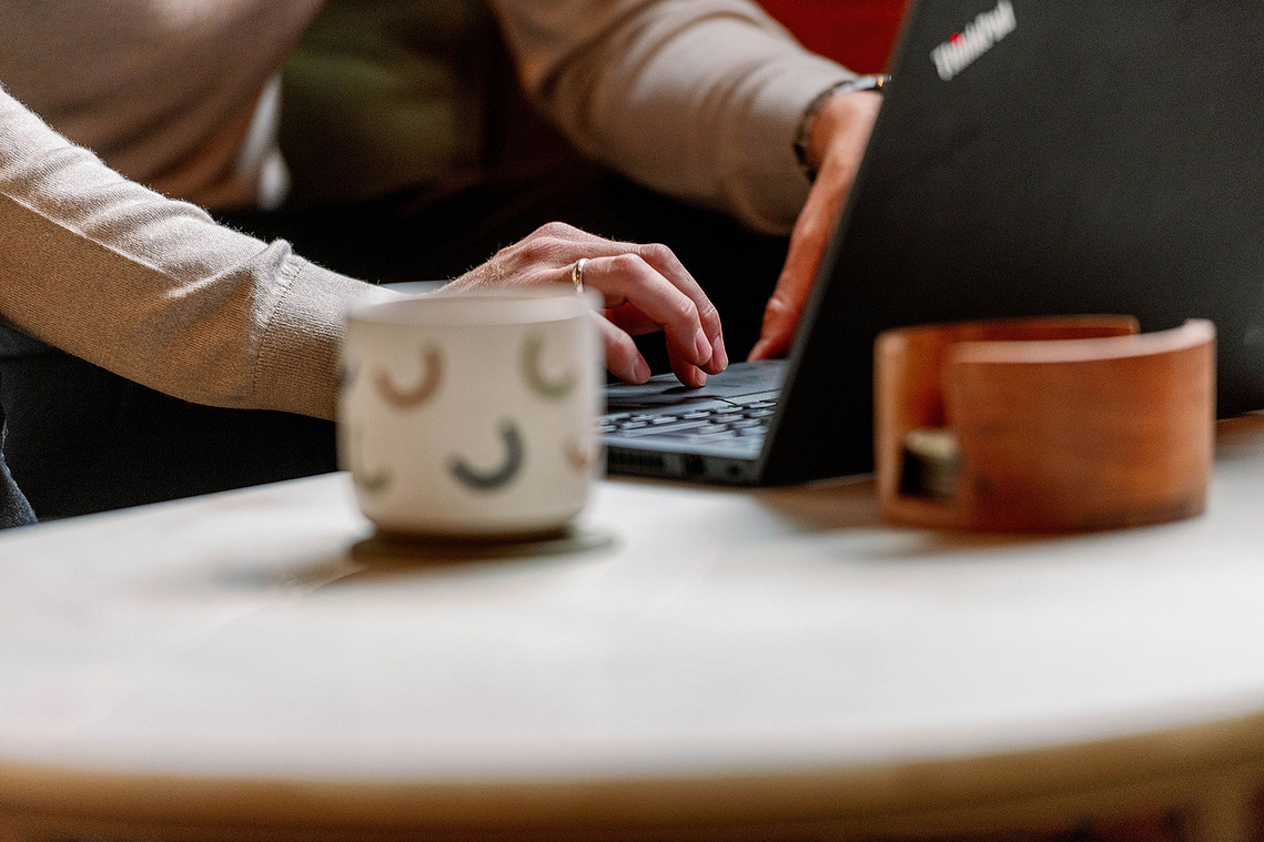 Lifestyle brand photography. Close up of laptop, hands and mug.