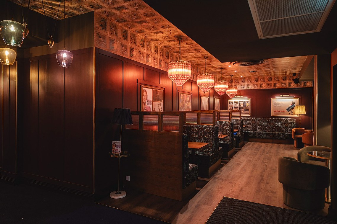 low light shot of cinema lobby with seated booths, ornate ceiling lights and patterned walls