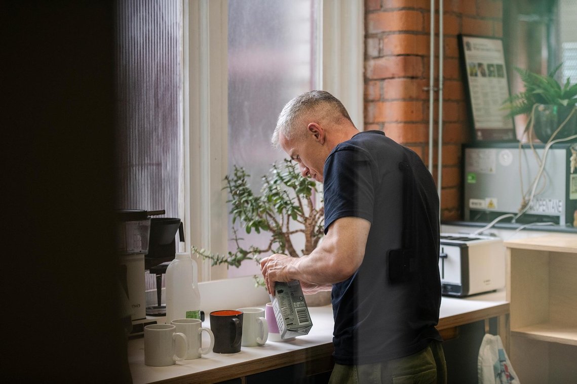 commercial lifestyle photography showing staff in a workplace, persona making drinks in kitchen space