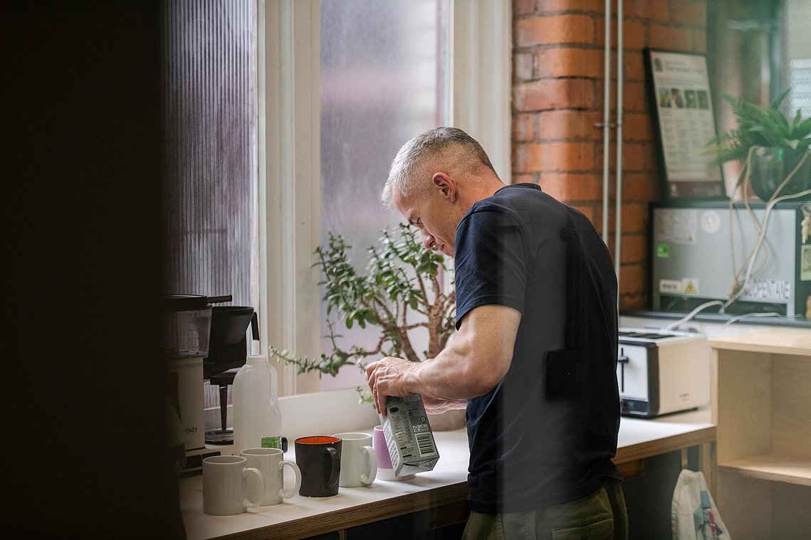 commercial lifestyle photography showing staff in a workplace, persona making drinks in kitchen space