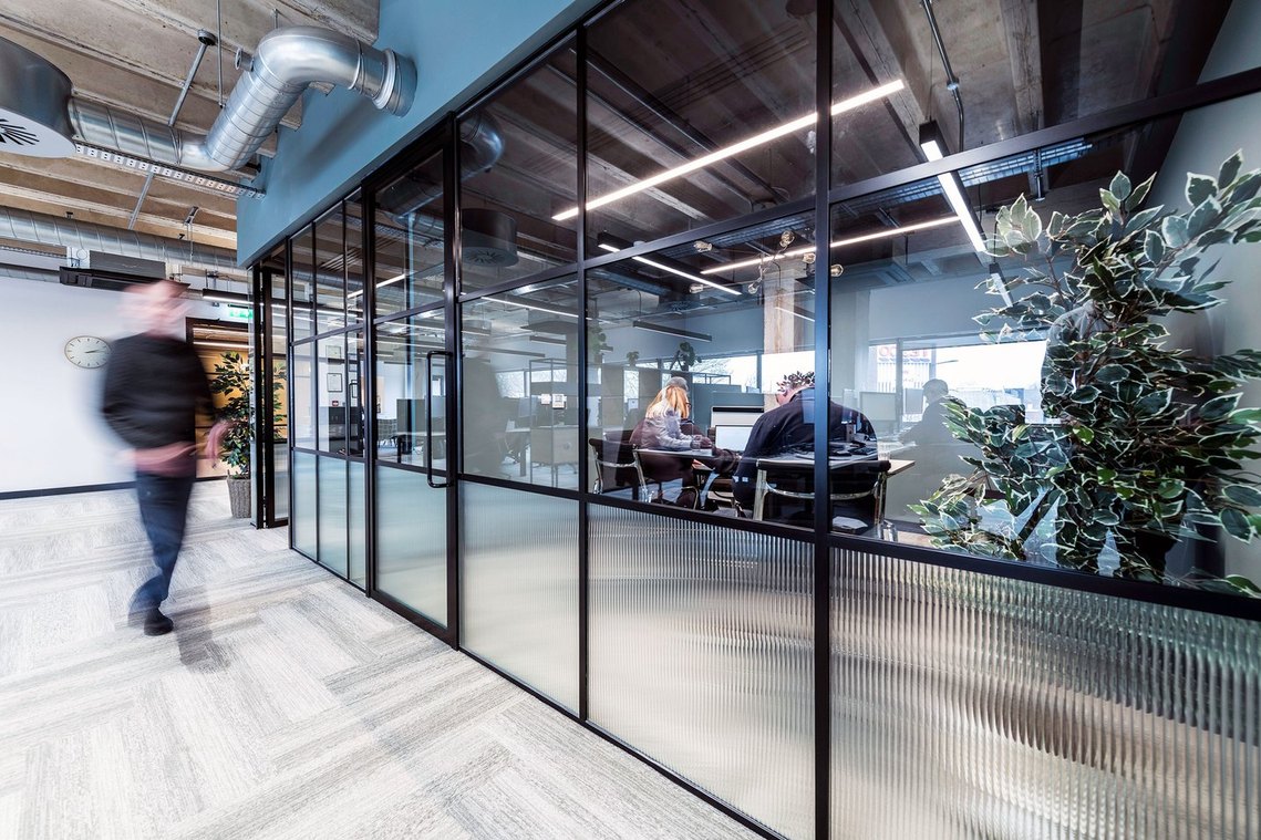 Modern office interior with glass walls and busy employees.