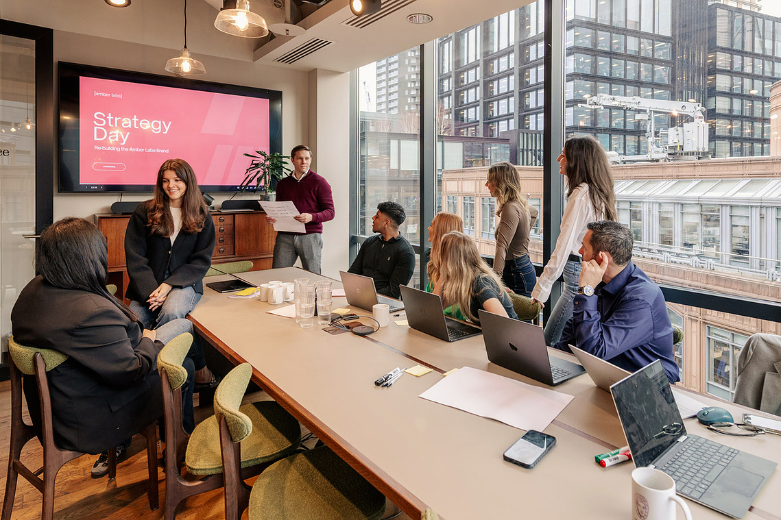 commercial lifestyle photography, informal office meeting with workers and laptops in glass office
