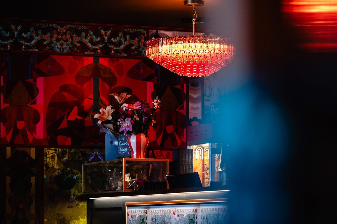 cinema reception with reds and blues, flowers and popcorn machine on counter and sign advertising cake