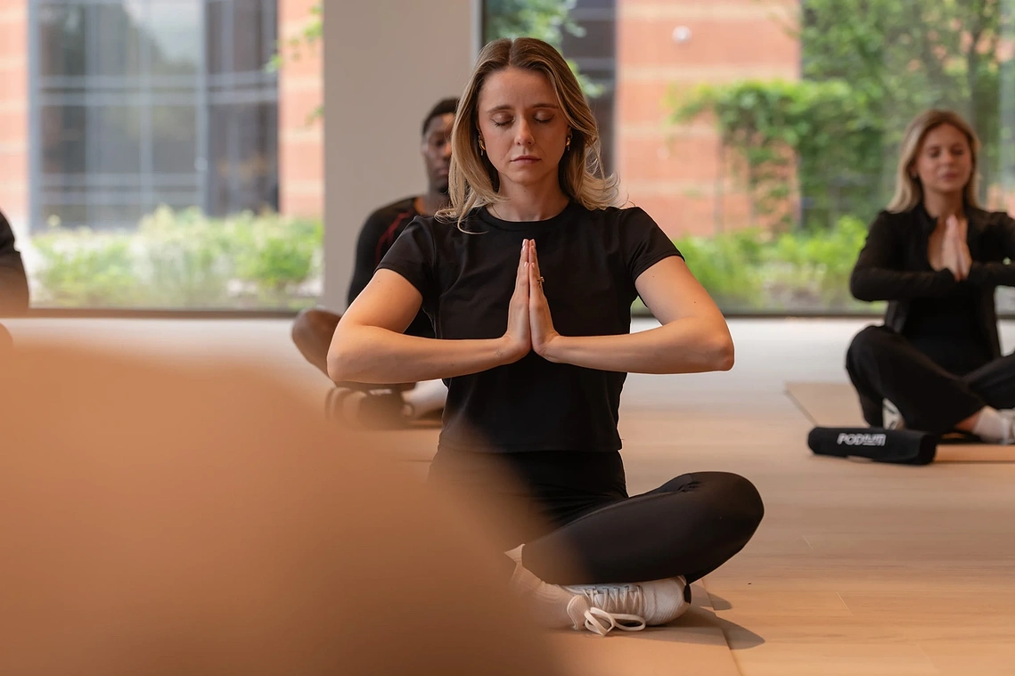 Woman meditating during a yoga session in Podium's wellness studio, Old Trafford, Manchester.