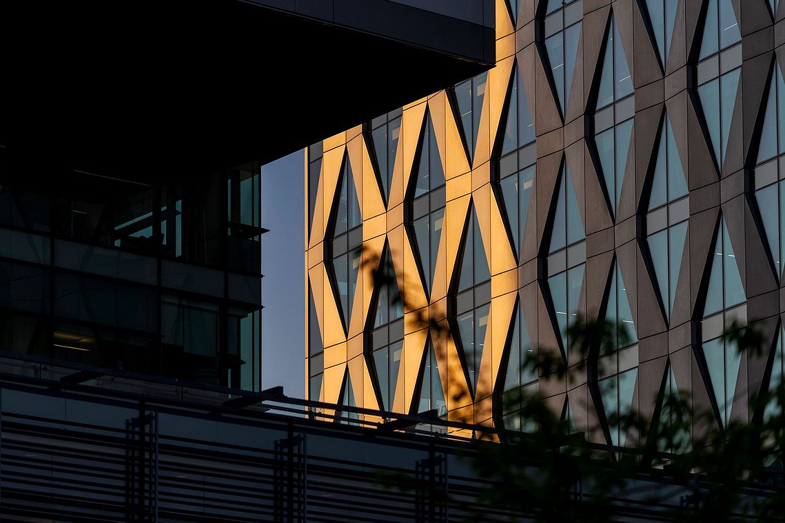architecture and lifestyle photography, modern glass high rise with patterned cladding, half lit by sunset, with shadows