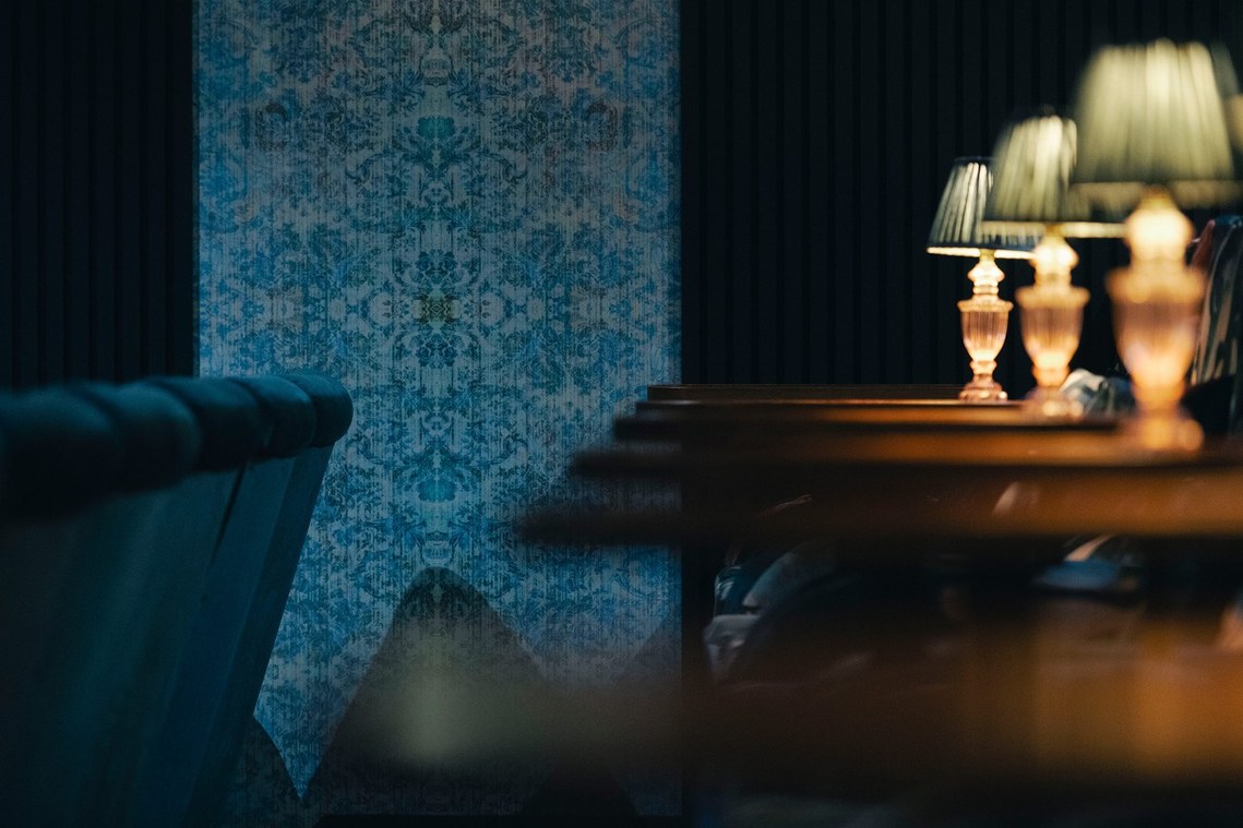 cropped photo of cinema interior, blue patterned walls and small table lamps surround the cinema seats