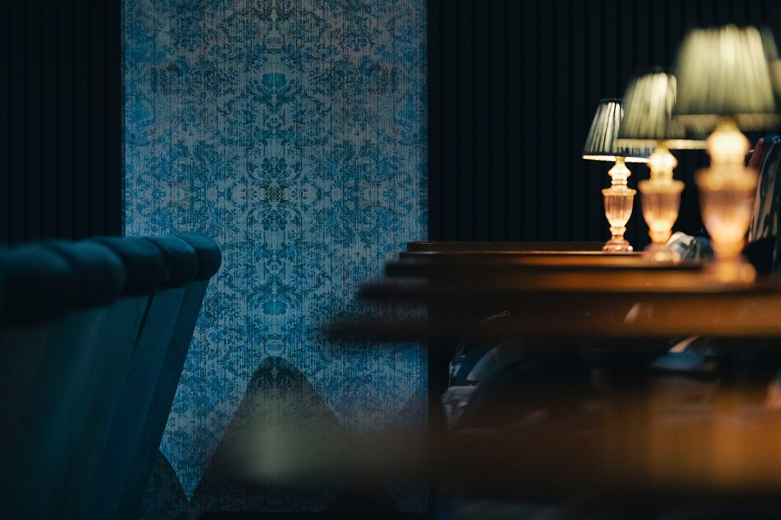 cropped photo of cinema interior, blue patterned walls and small table lamps surround the cinema seats