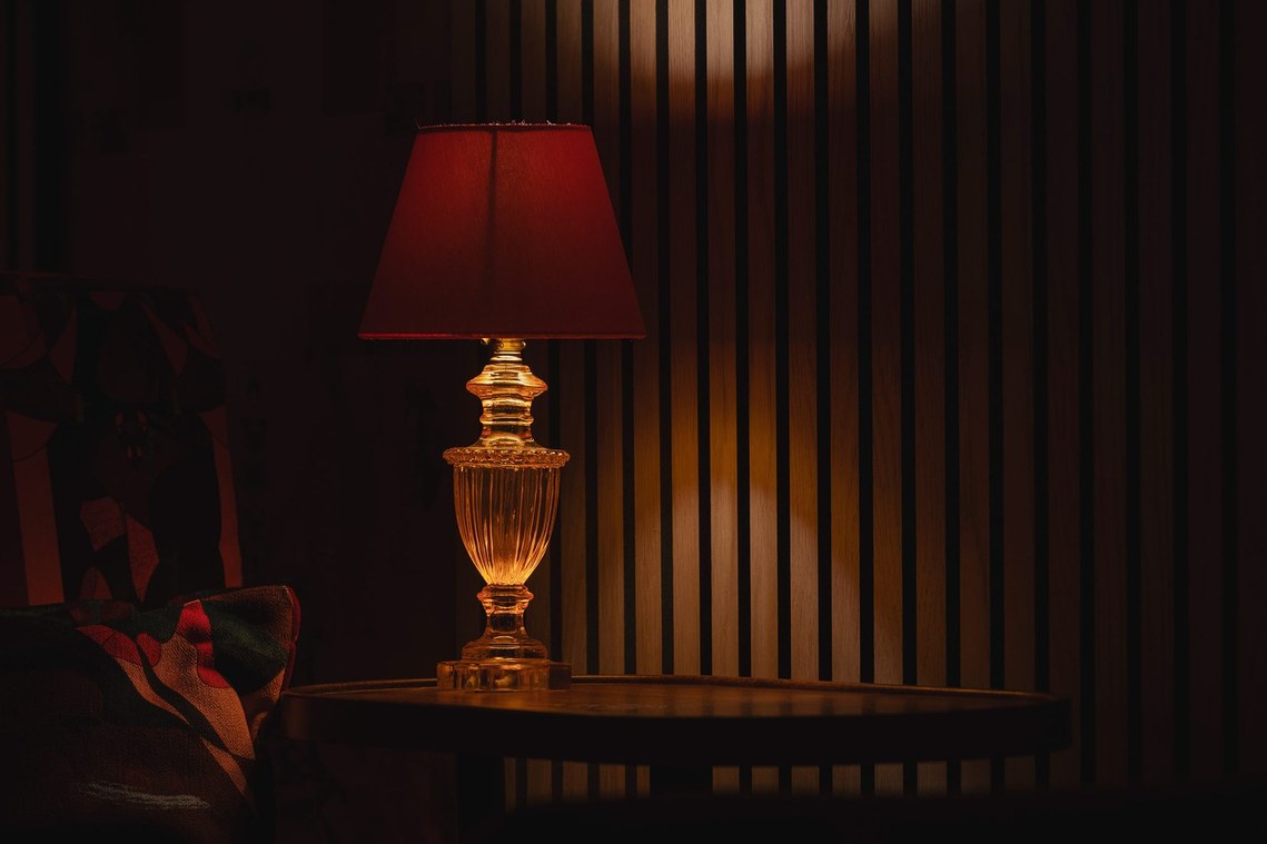 close in photo of cinema interior, red hues dominate with wooden slatted walls and red table lamp