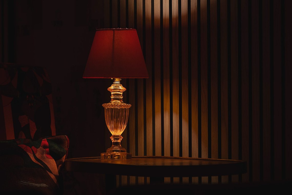 close in photo of cinema interior, red hues dominate with wooden slatted walls and red table lamp