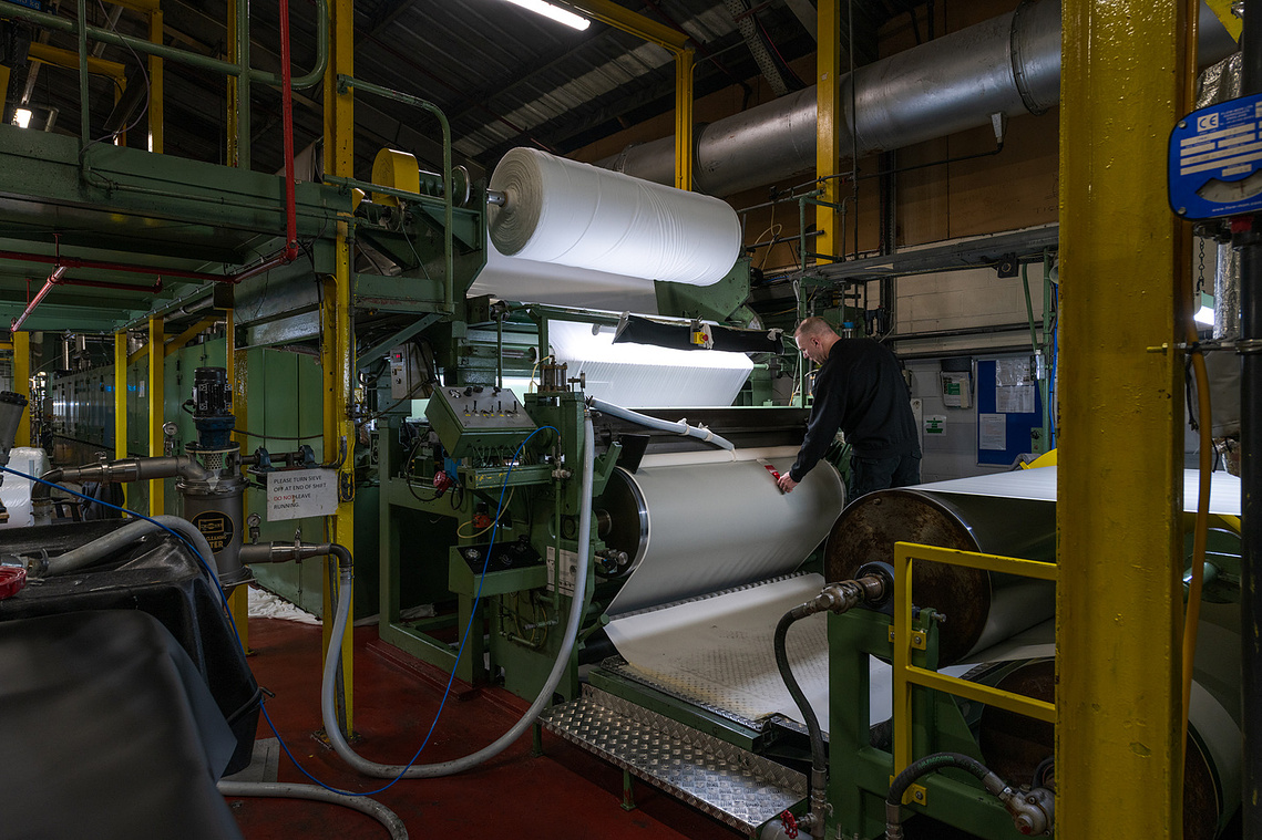 Documentary manufacturing photography capturing a factory worker operating machinery with attention to detail.