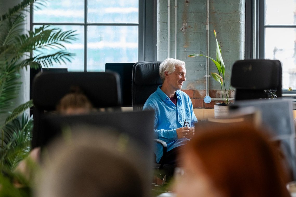 commercial lifestyle photography showing staff in a workplace, candid portrait of person sat in office chair in conversation
