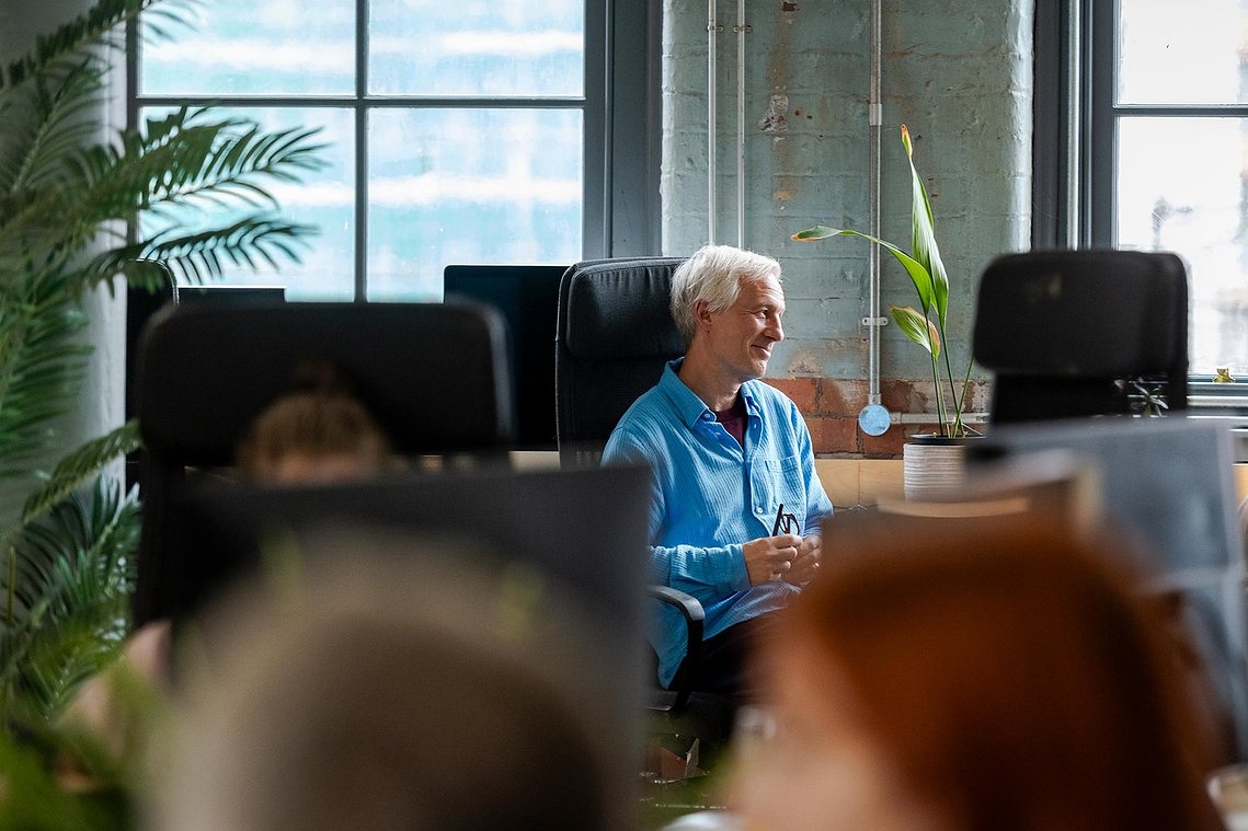 commercial lifestyle photography showing staff in a workplace, candid portrait of person sat in office chair in conversation