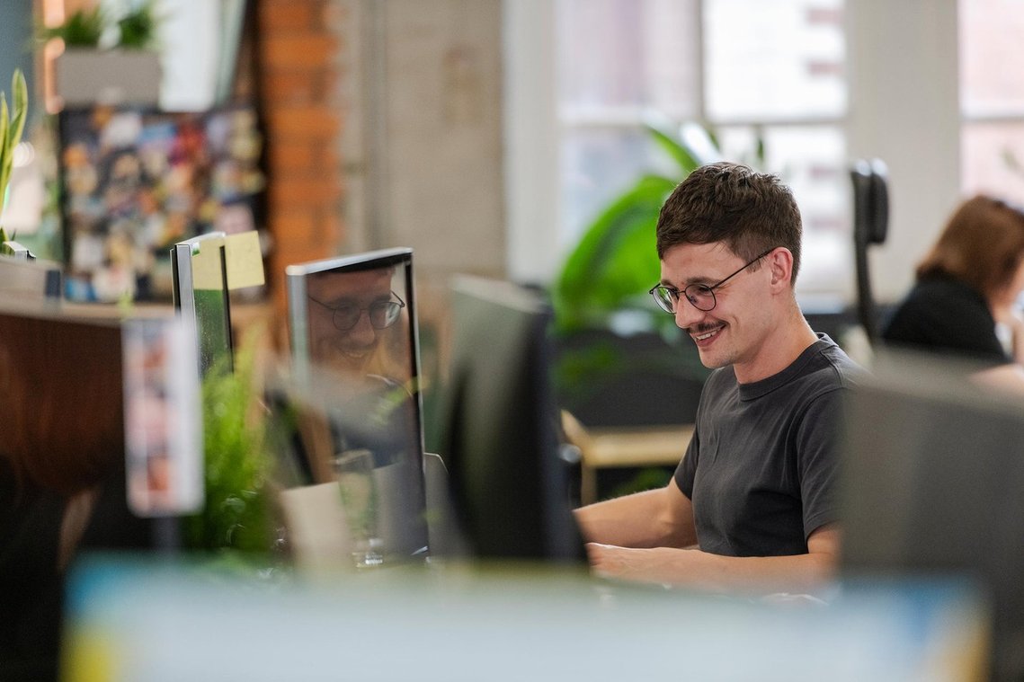 commercial lifestyle photography showing staff in a workplace, candid photograph shot from far away shows person at desk working 