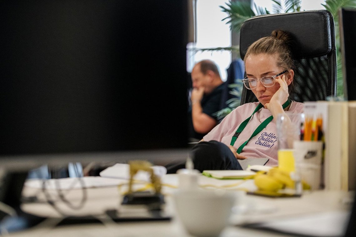 commercial lifestyle photography showing staff in a workplace, candid staff portrait of person sat at desk with laptop on lap
