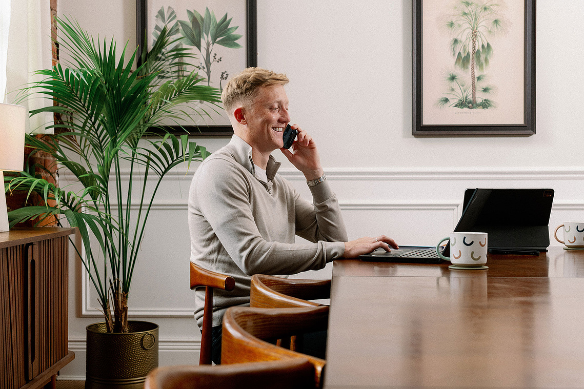 Professional yet relaxed brand photography Manchester. Man on phone in office with plants