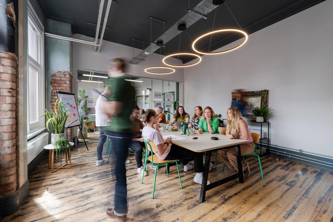 commercial lifestyle photography showing staff in a workplace, team members sat around table in meeting space