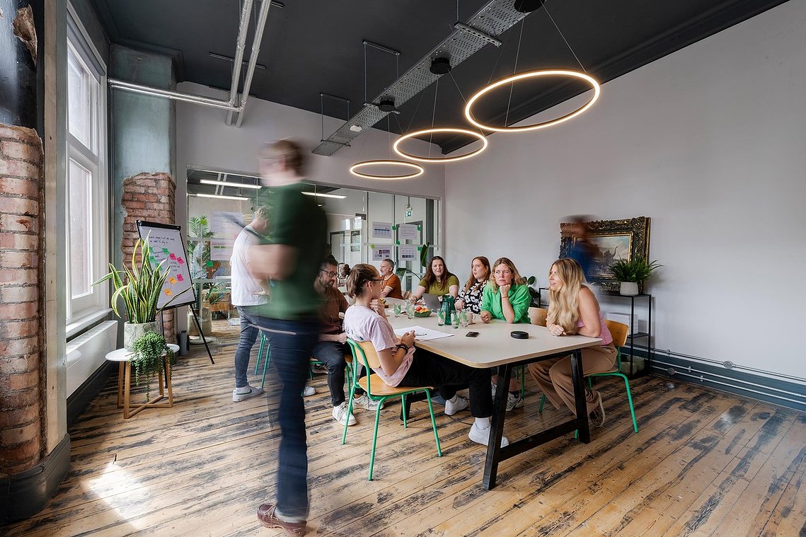 commercial lifestyle photography showing staff in a workplace, team members sat around table in meeting space