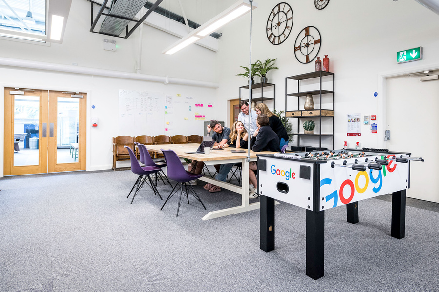 Modern office space with a foosball table and a meeting area.