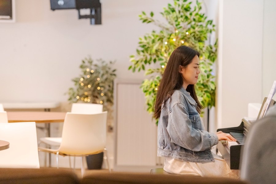 student lifestyle photography, girl sits at piano smiling as she plays