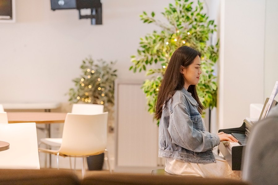 student lifestyle photography, girl sits at piano smiling as she plays