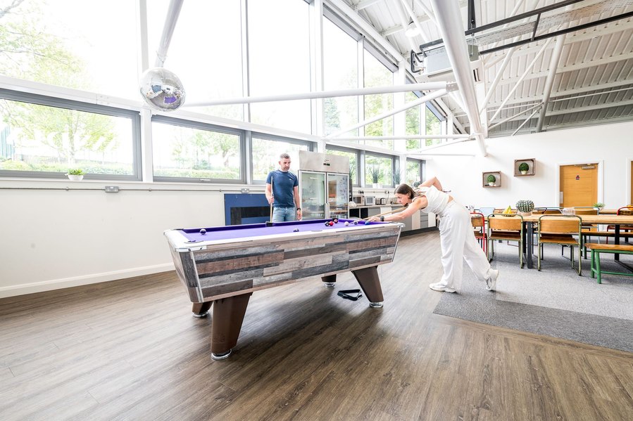 Two people playing pool in a brightly lit game room with modern decor.