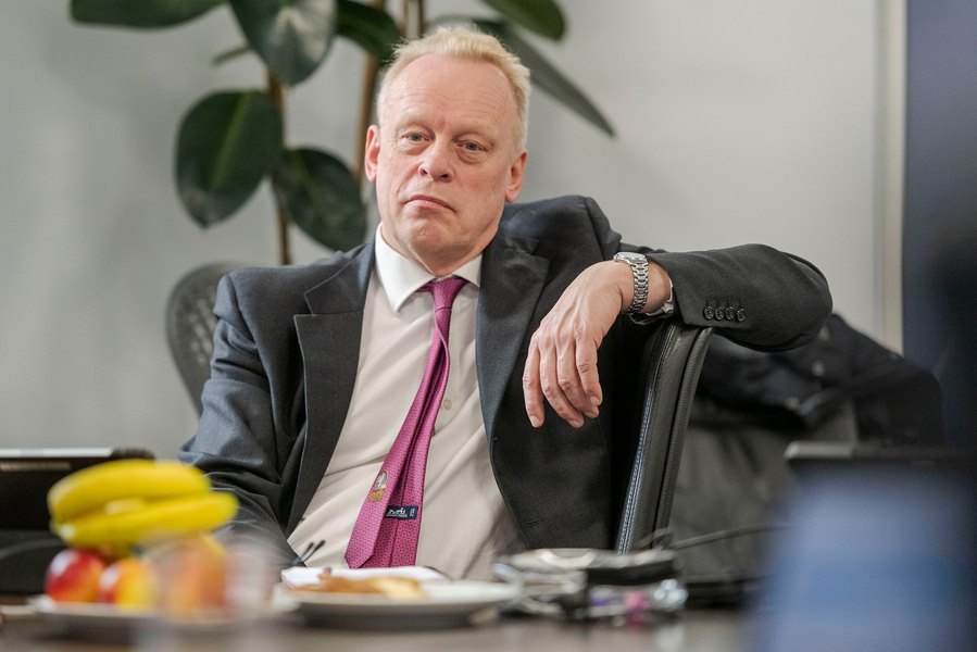 A person in a suit and pink tie sits at a table looking attentively. Capturing the essence of relaxed corporate photography, showcasing the skill of a Manchester commercial photographer