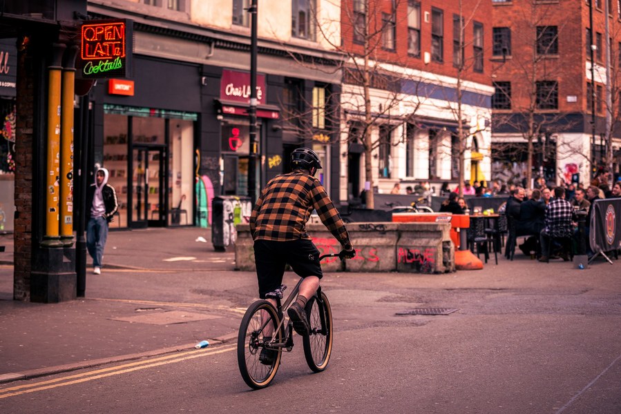 placemaking photography. manchester. norther quarter. architecture. man cycles through area