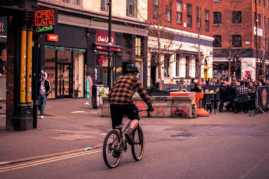placemaking photography. manchester. norther quarter. architecture. man cycles through area
