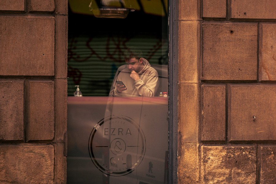 placemaking photography. manchester. norther quarter. architecture. man sits in window of cafe