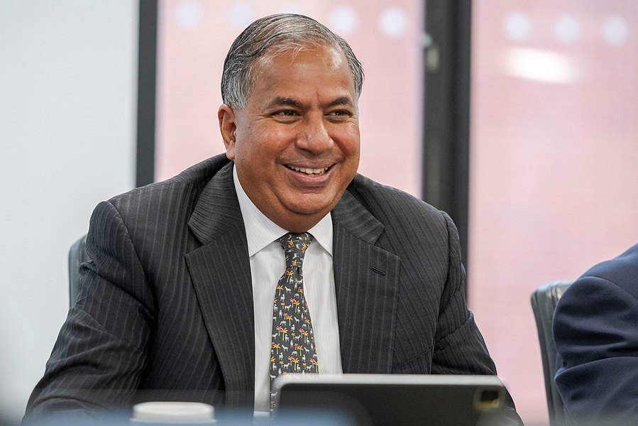 A person in a suit is smiling while seated at a table. The scene beautifully captures the essence of relaxed corporate photography.
