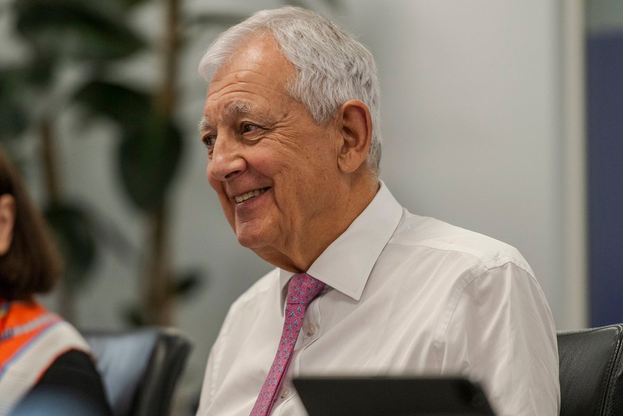 A man in a white shirt and pink tie smiling with a relaxed confidence. Captured by a Manchester commercial photographer, this image shows relaxed corporate photography.