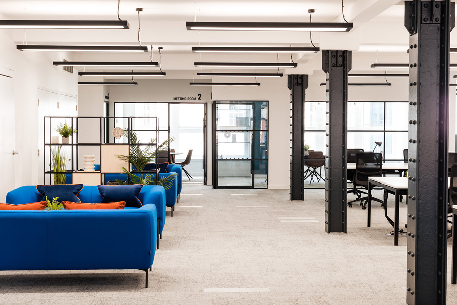 open plan office space in commercial office property. blue sofas in breakout spaces and original period features are visible