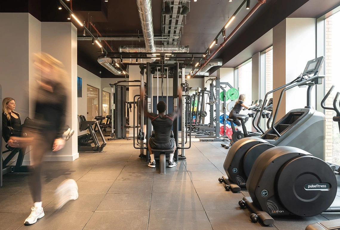 Wide view of Podium's residents' gym in Old Trafford with natural movement and cardio equipment. Commercial property photography.