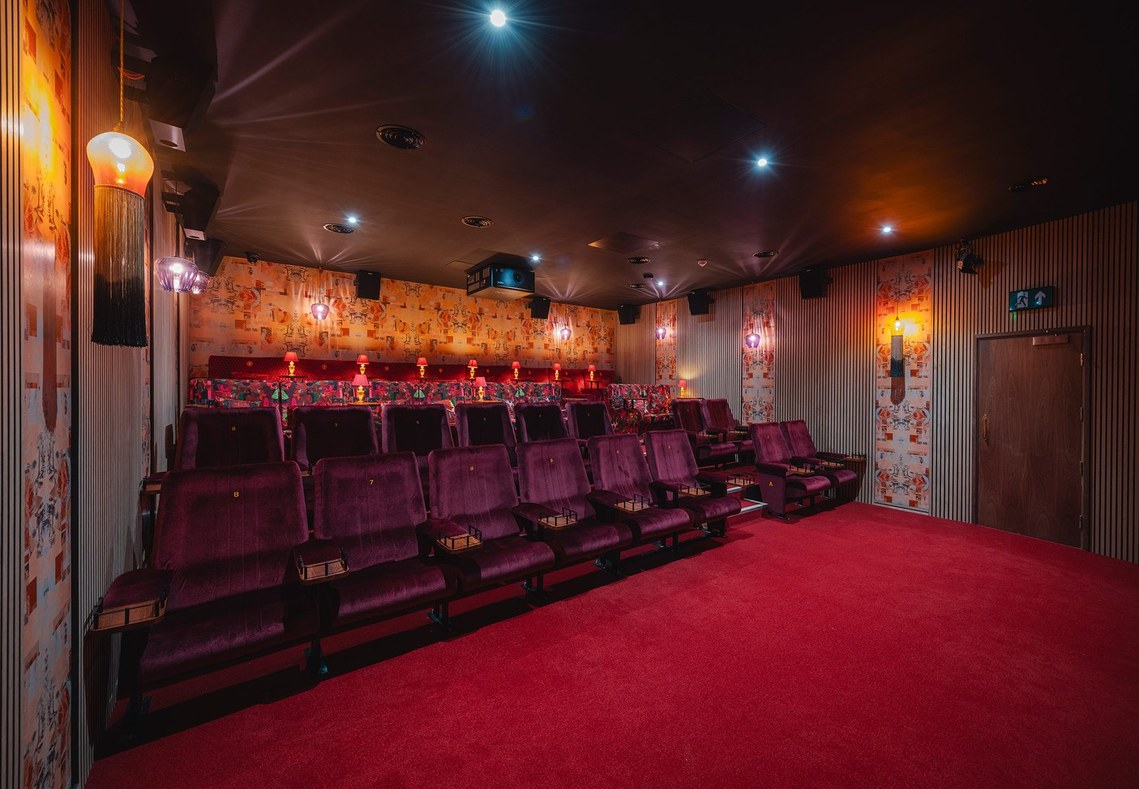 interior photography showing a red cinema auditorium with plush rows of seats and red carpets