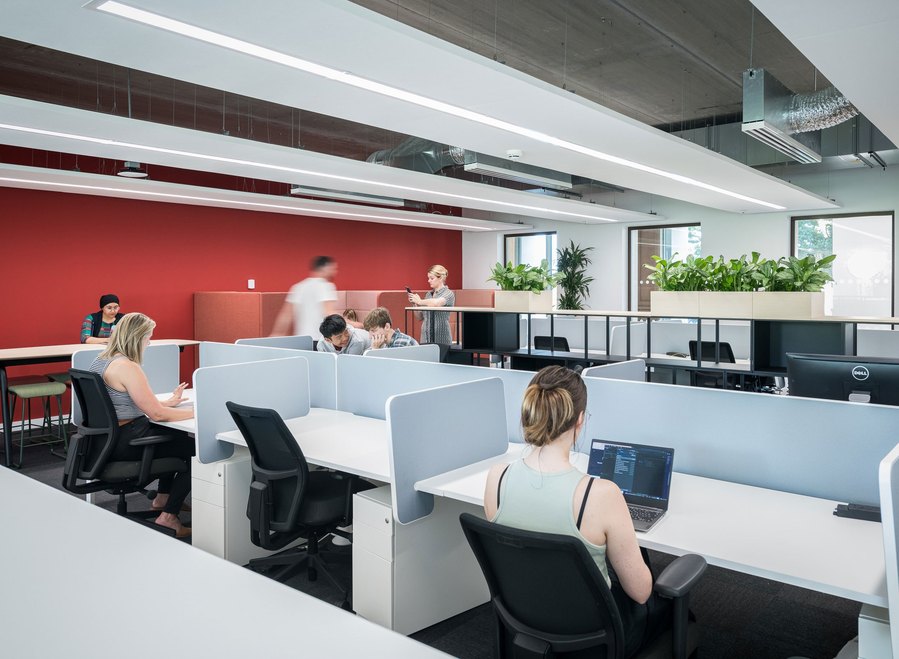 Modern office space with employees working at desks and ambient lighting.