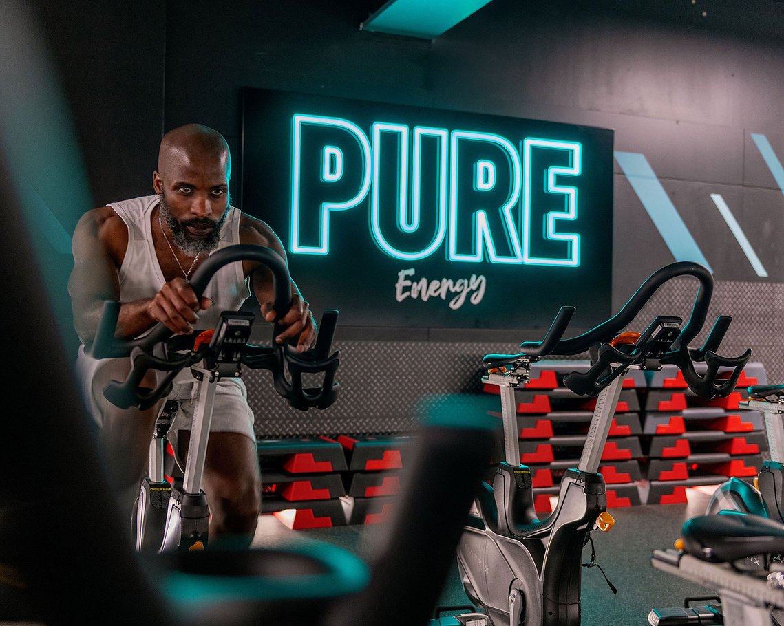 PureGym facility inside 3 Hardman Street building photographed during lifestyle shoot. Man on cycle machine
