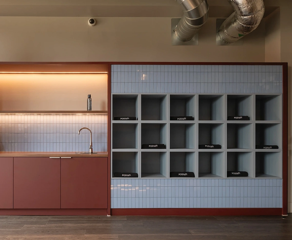 Wellness studio towel station with branded Podium towels and tiled kitchenette, Old Trafford, Manchester.