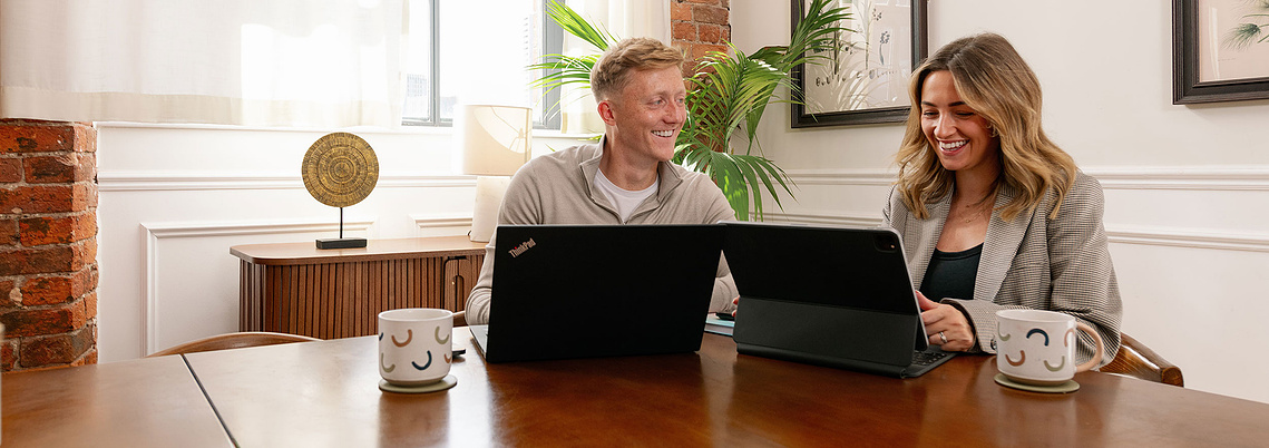 Brand storytelling through lifestyle photography for small business. Smiling couple with laptops sit in stylish office space