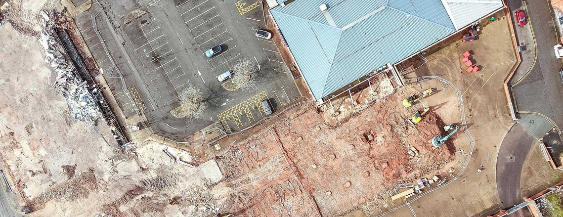 demolition site on shopping centre site, interior of building exposed by works. drone shot from above
